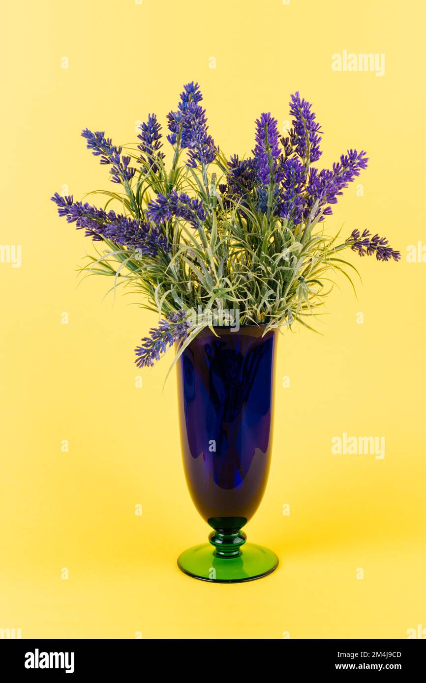 Artificial lavender in vase on yellow background Stock Photo