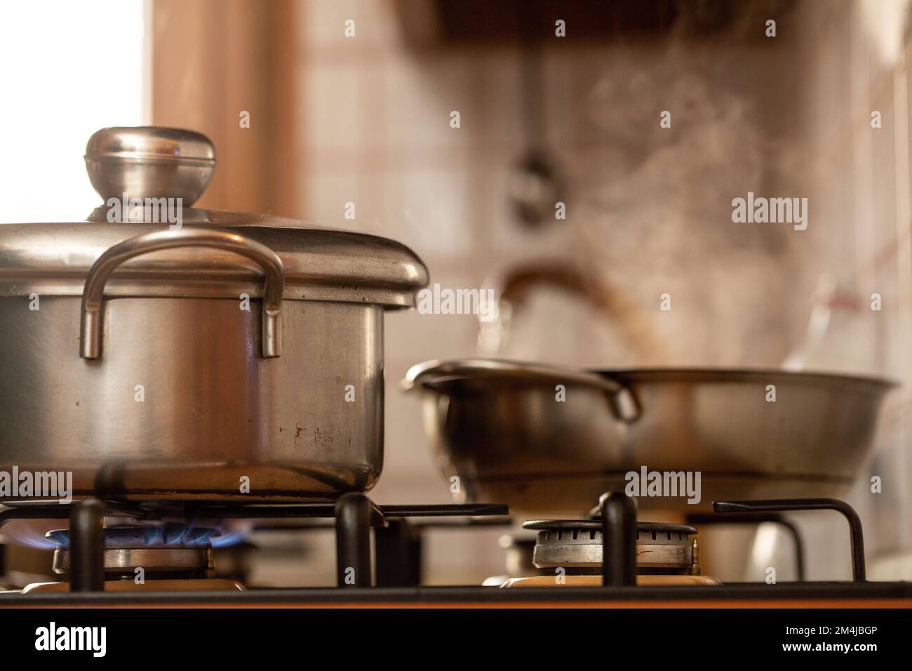 Cook with old pots on the stove with steam from boiling water. Vintage