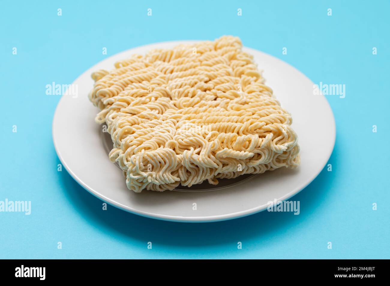 dry fresh noodle cubes on white small dish Stock Photo