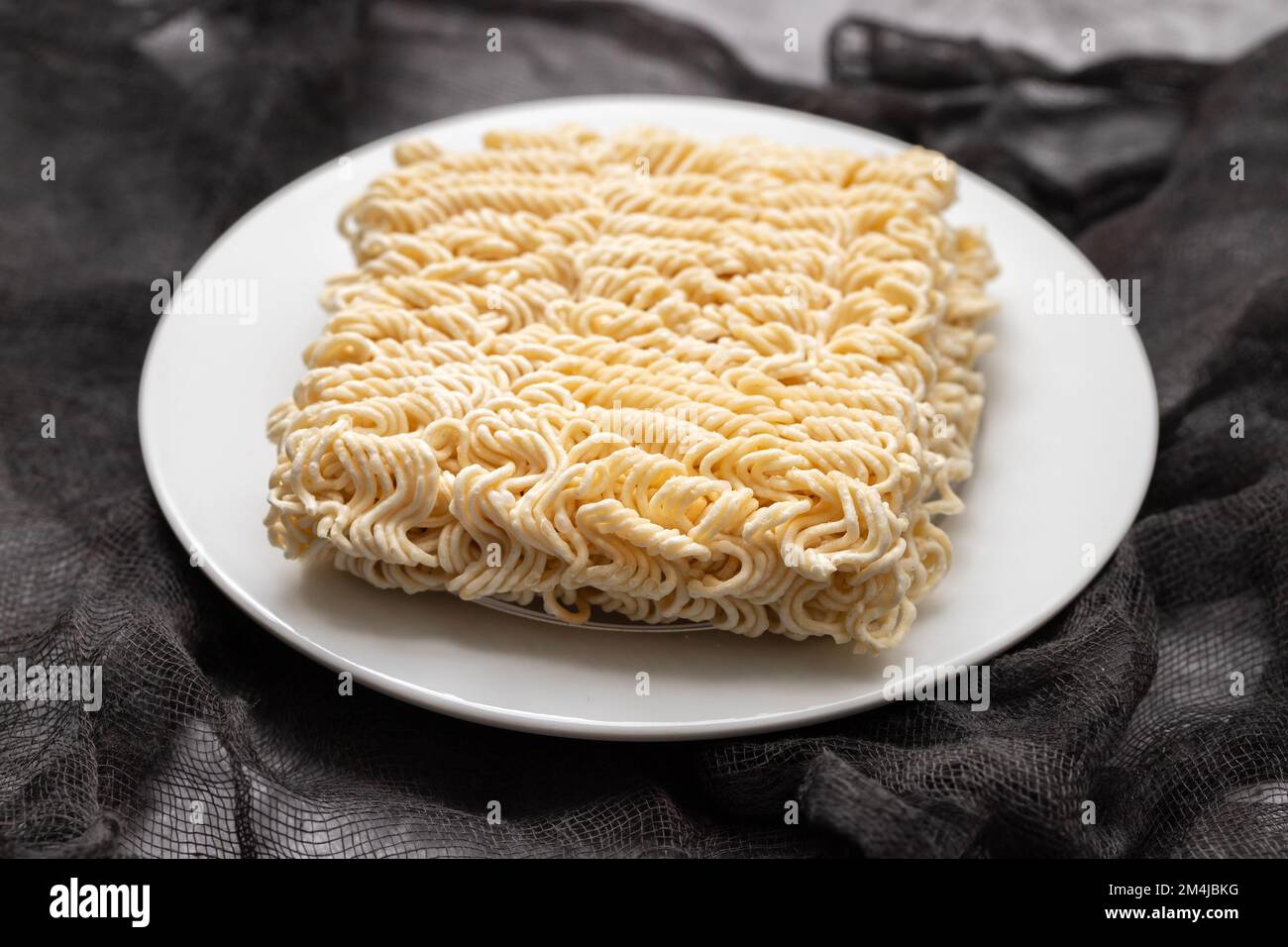 dry fresh noodle cubes on white small dish Stock Photo