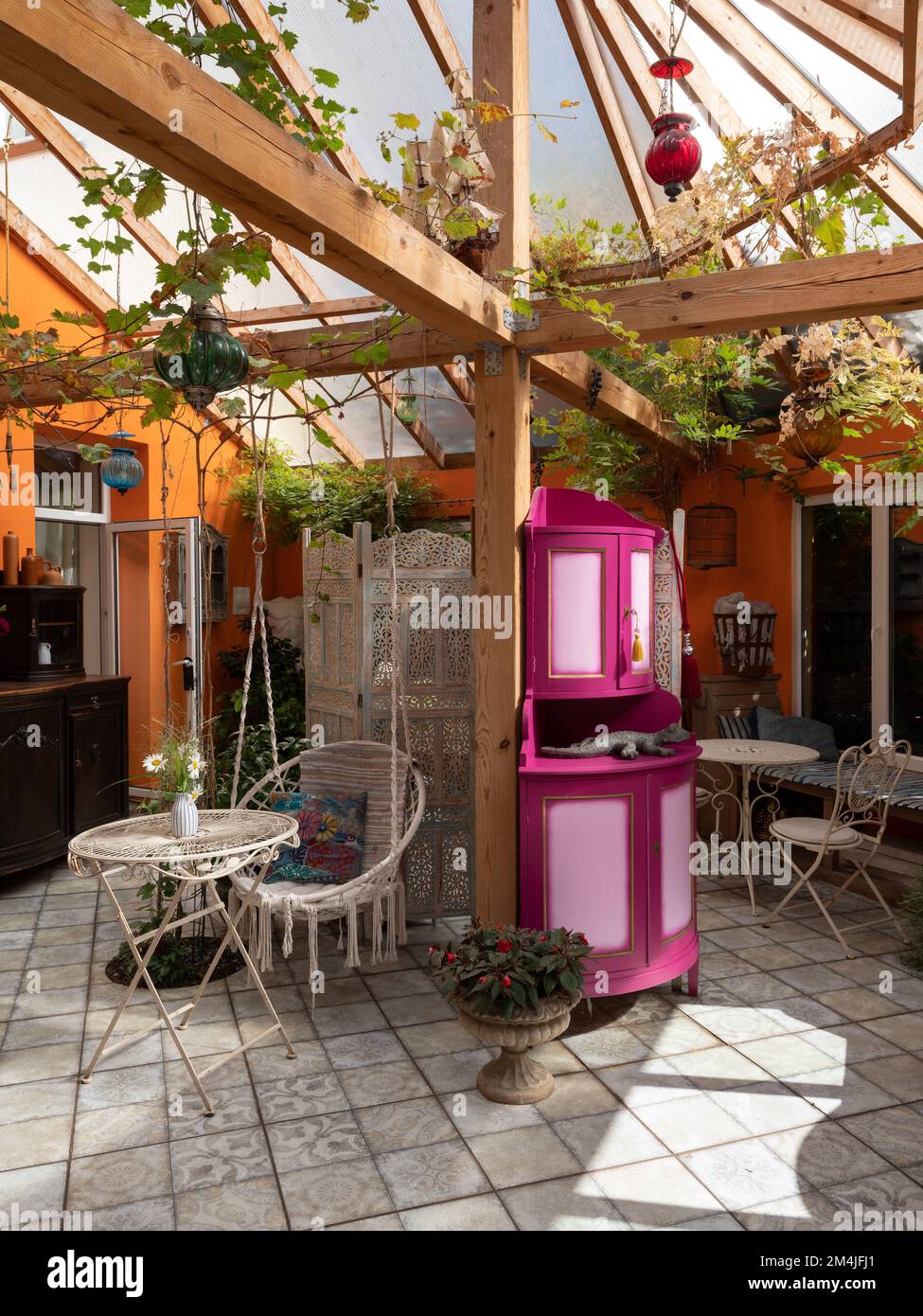 Interior of veranda. Wooden furniture. Hanging wicker chair, plants