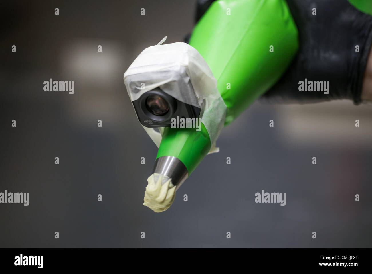 cake chef designer using pistachio cream filling piping bag on layered