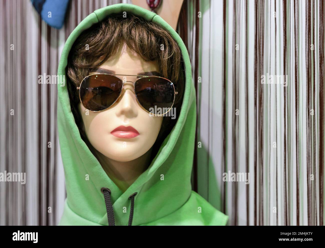 Female mannequin in sunglasses and a green hoodie. Stock Photo