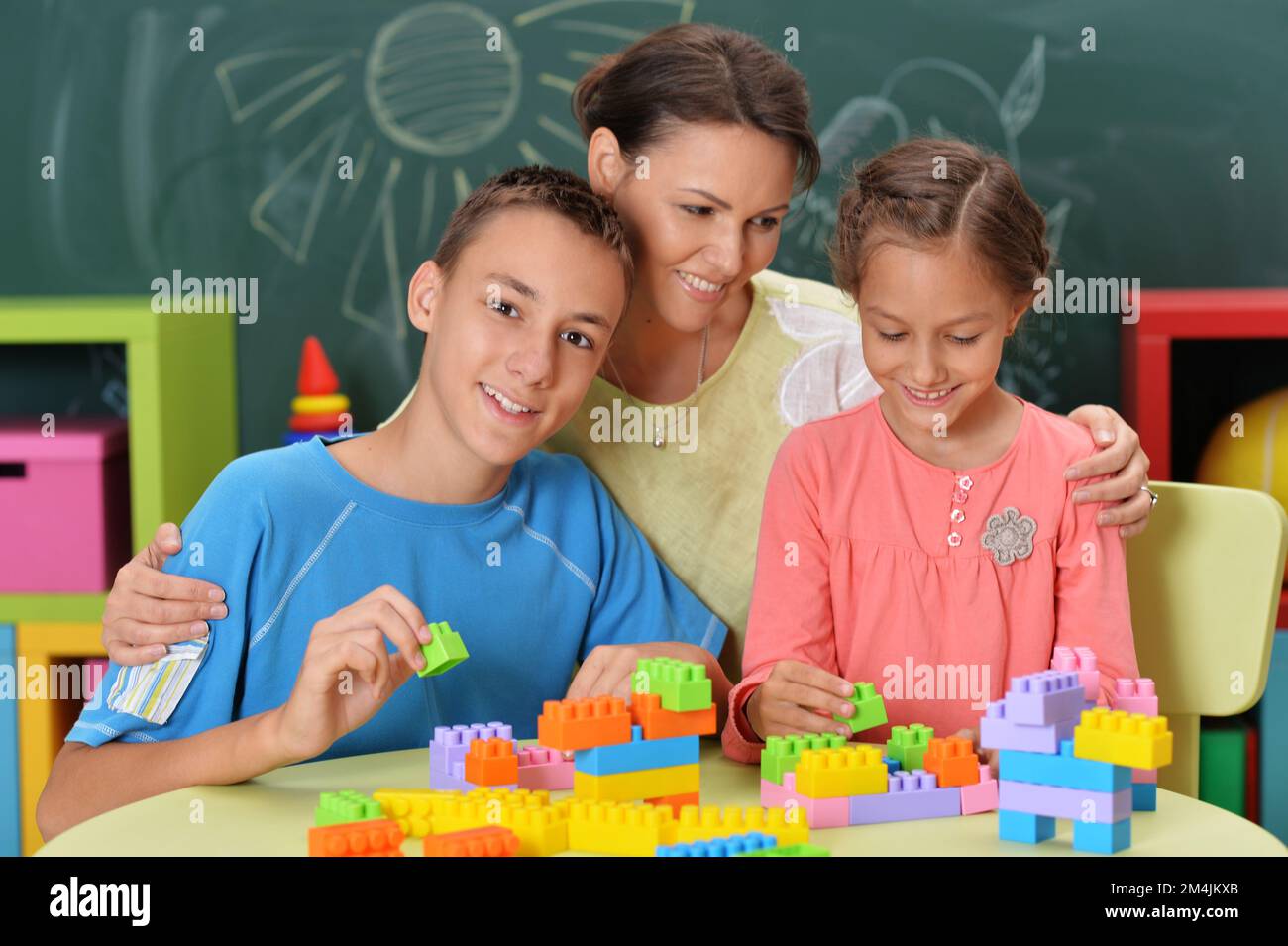 Mother and children playing with colorful plastic blocks Stock Photo ...