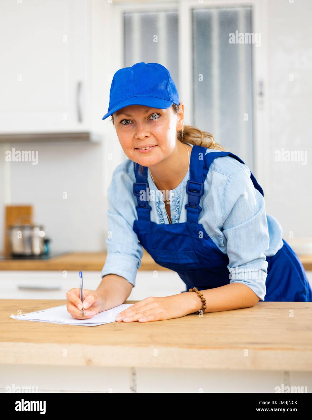 Woman house cleaner making notes in kitchen Stock Photo