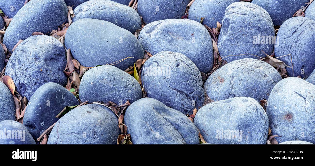 background of blue stones with dried leaves fallen between in a garden Stock Photo