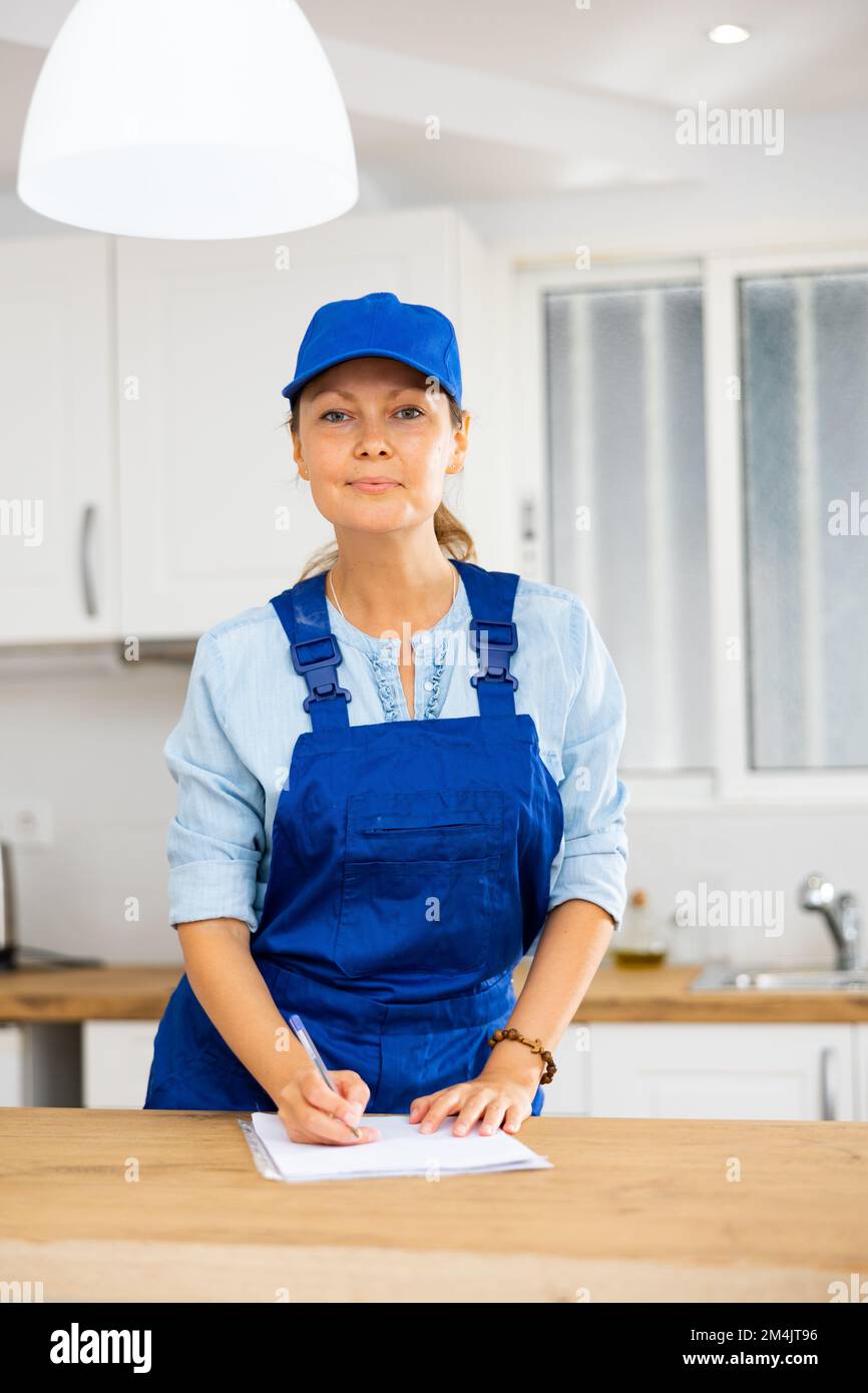 Woman house cleaner making notes in kitchen Stock Photo
