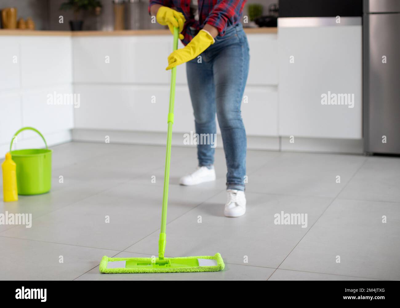 Millennial african american lady in rubber gloves with bucket and mop washes floor, enjoys household chores Stock Photo