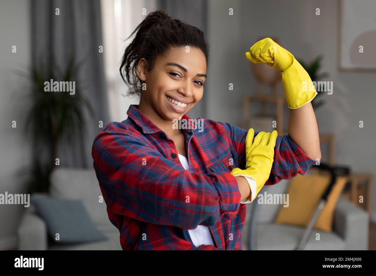 Glad millennial african american woman in rubber gloves shows strength