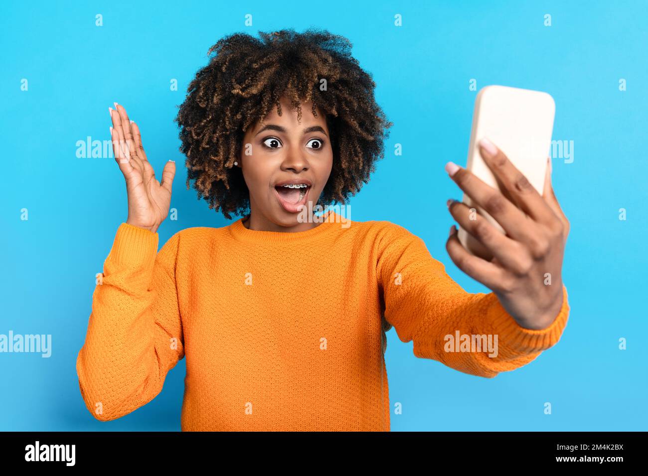 Emotional young black woman holding cell phone and exclaiming Stock Photo