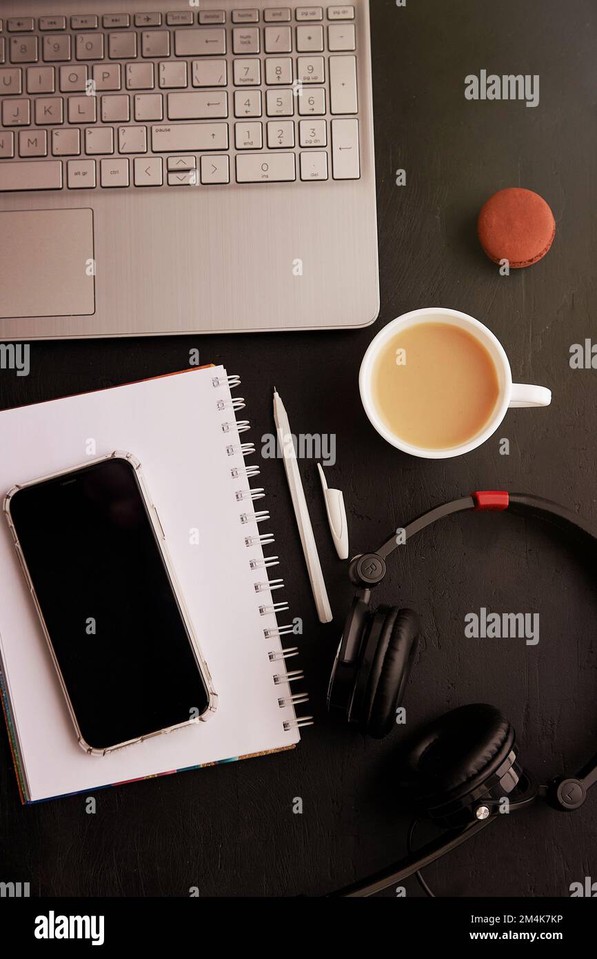 Mock up of phone screen, laptop, headphones, cup of coffee, macaroons. Freelance lifestyle, taking webinar, working remotely, listening music, studying . Stock Photo