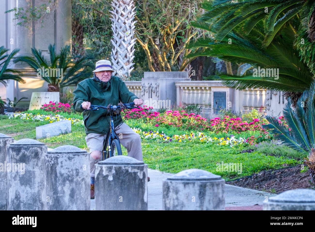 NEW ORLEANS, LA, USA - DECEMBER 16, 2022: Senior Citizen haphazardly rides bicycle on the sidewalk in front of Audubon Park instead of the bike lane Stock Photo