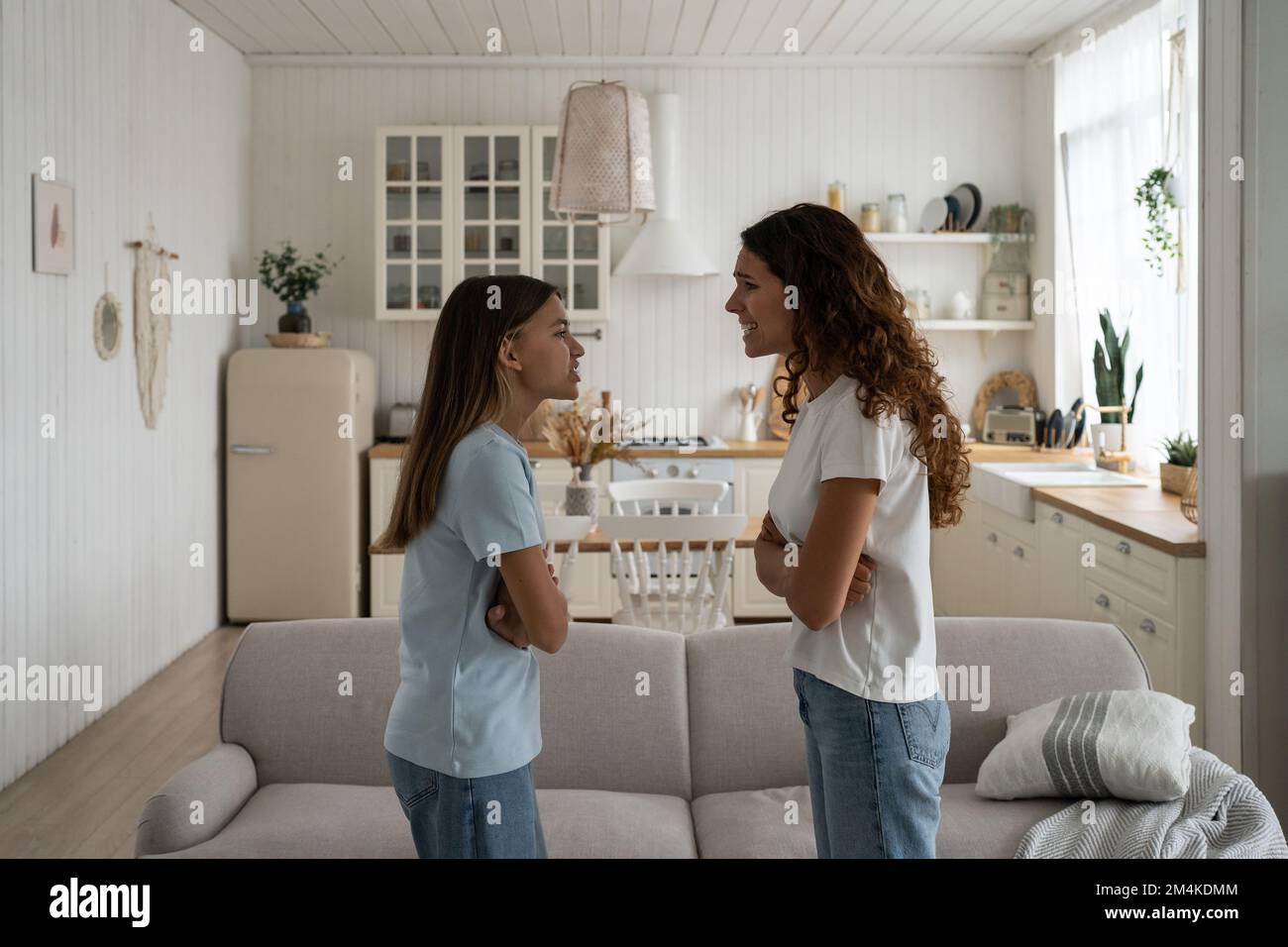 Troubled teen girl daughter and mother quarreling arguing at home, yelling at each other Stock Photo