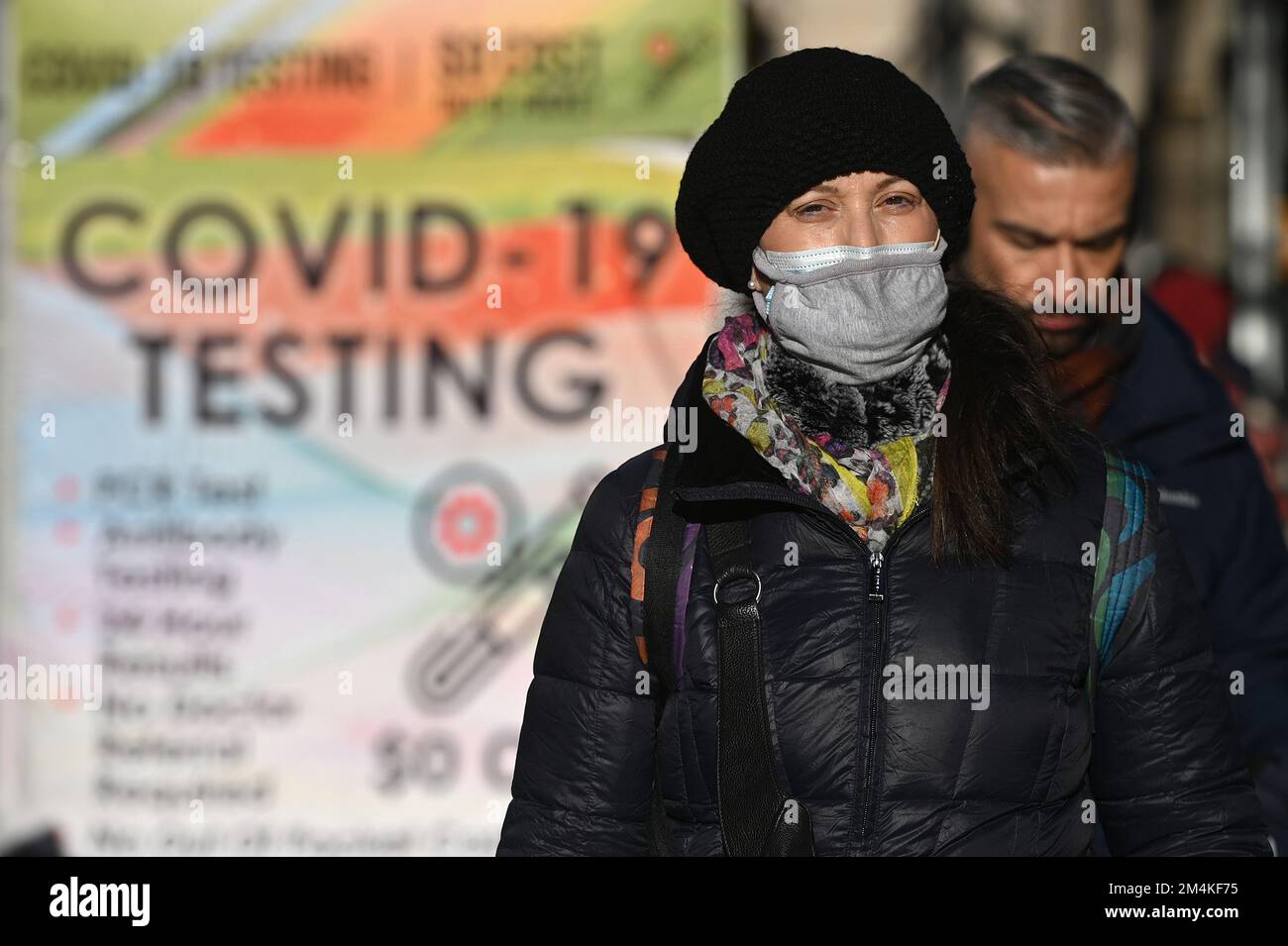 New York, USA. 21st Dec, 2022. A woman wears two masks as walks down