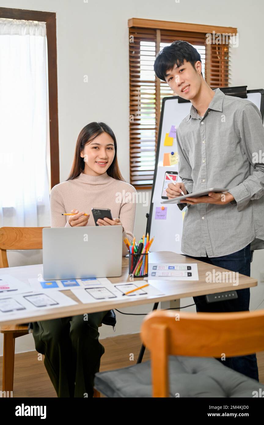 Attractive and professional millennial Asian male and female developers are in the meeting room, smiling and looking at the camera. Stock Photo
