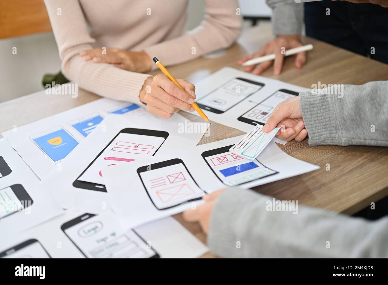 A team of mobile app developers and designers are discussing and brainstorming on their new mobile app interface design. cropped image Stock Photo