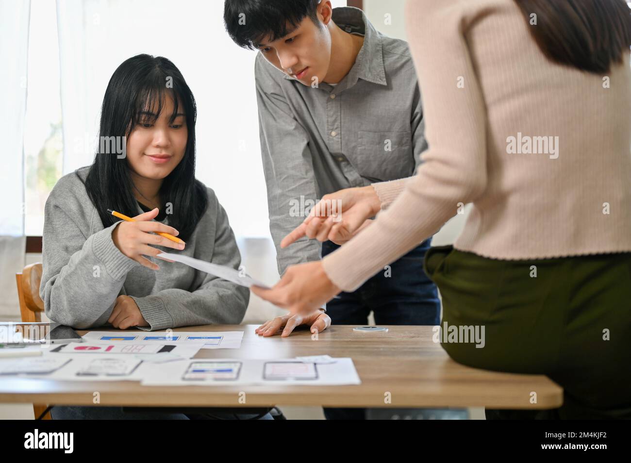 Group of millennial Asian mobile application developers startup are in the meeting, discussing and brainstorming on their new project, testing new pro Stock Photo