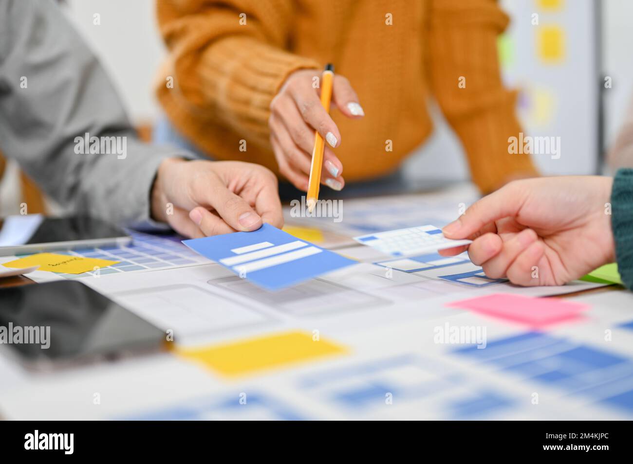 close-up image, A professional female graphic designer pointing her pen on paper, discussing and brainstorming a new prototype with her team. Stock Photo