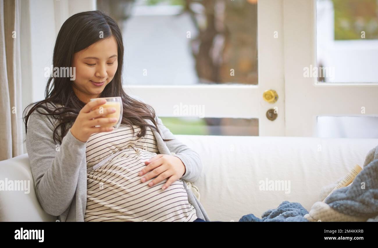 Great expectations. an attractive young pregnant woman drinking an iced