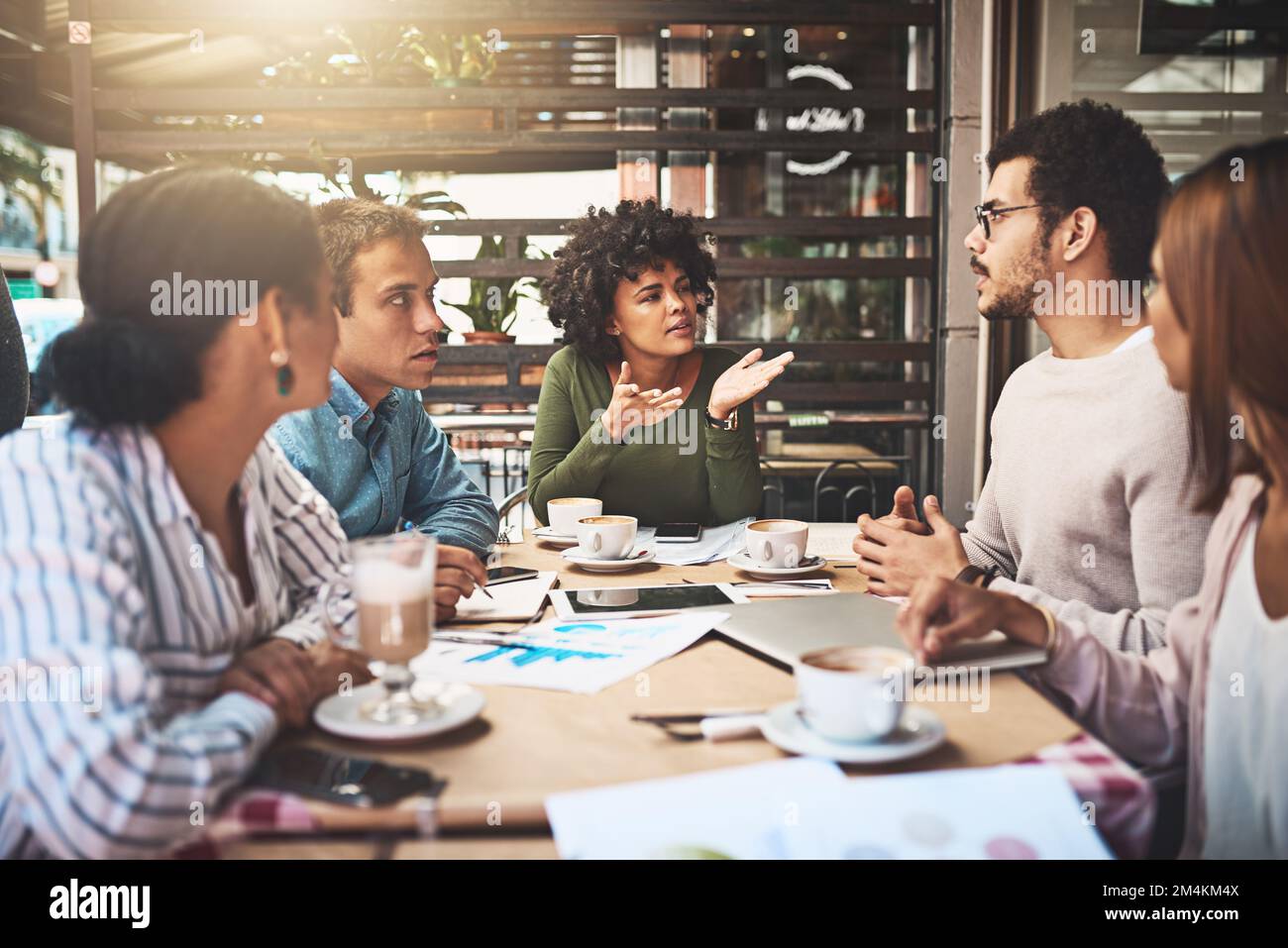 Please share your thoughts guys. a group of focused young work colleagues having a discussion at a meeting together while being seated around a table. Stock Photo