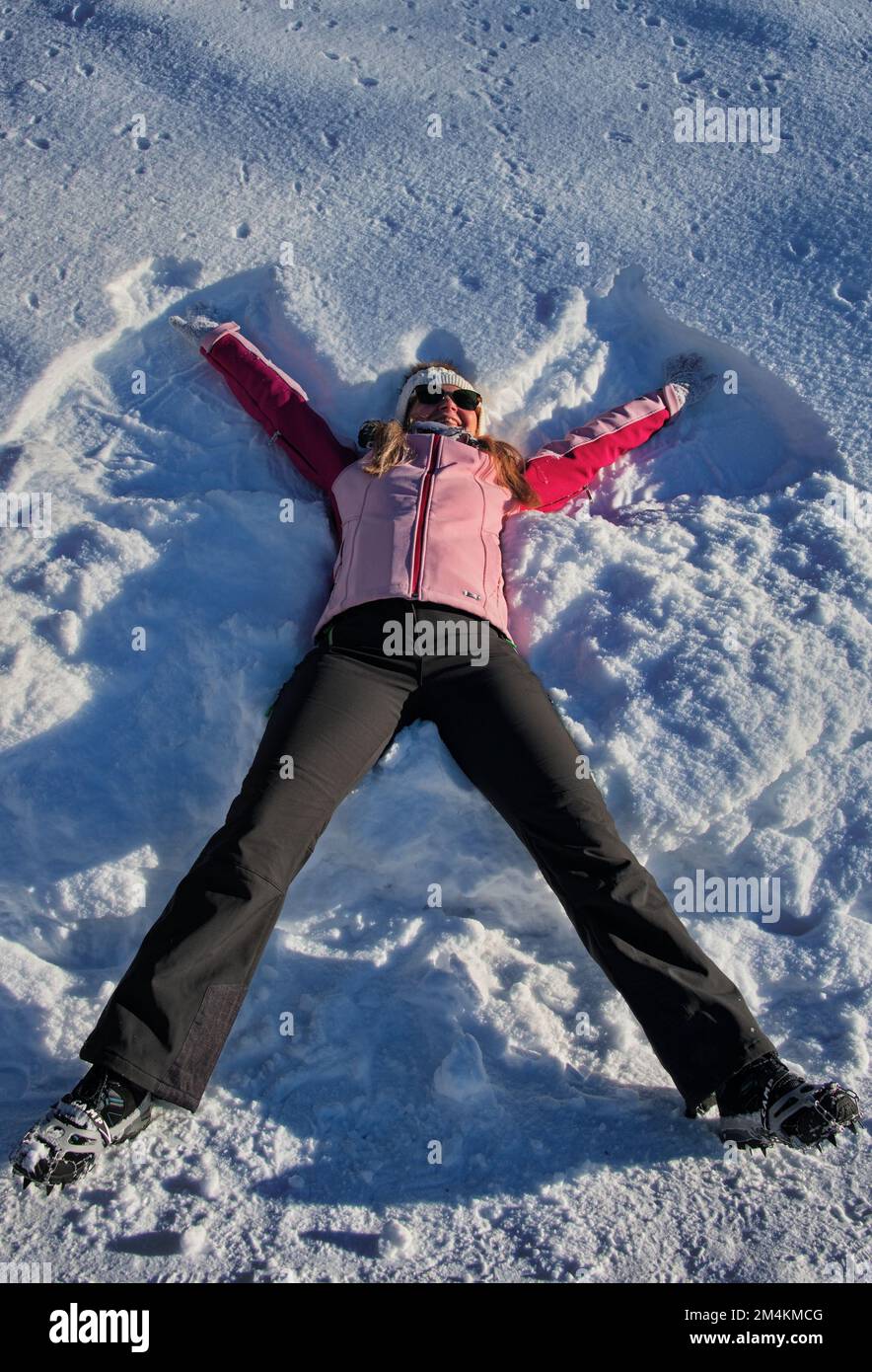 Mature woman having fun lying in snow, Austria Stock Photo
