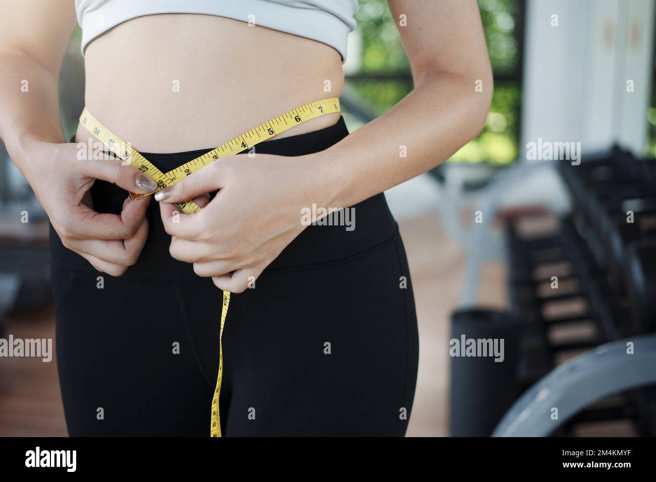 https://c8.alamy.com/comp/2M4KMYF/young-woman-measuring-her-waist-by-measure-tape-at-the-gym-2M4KMYF.jpg