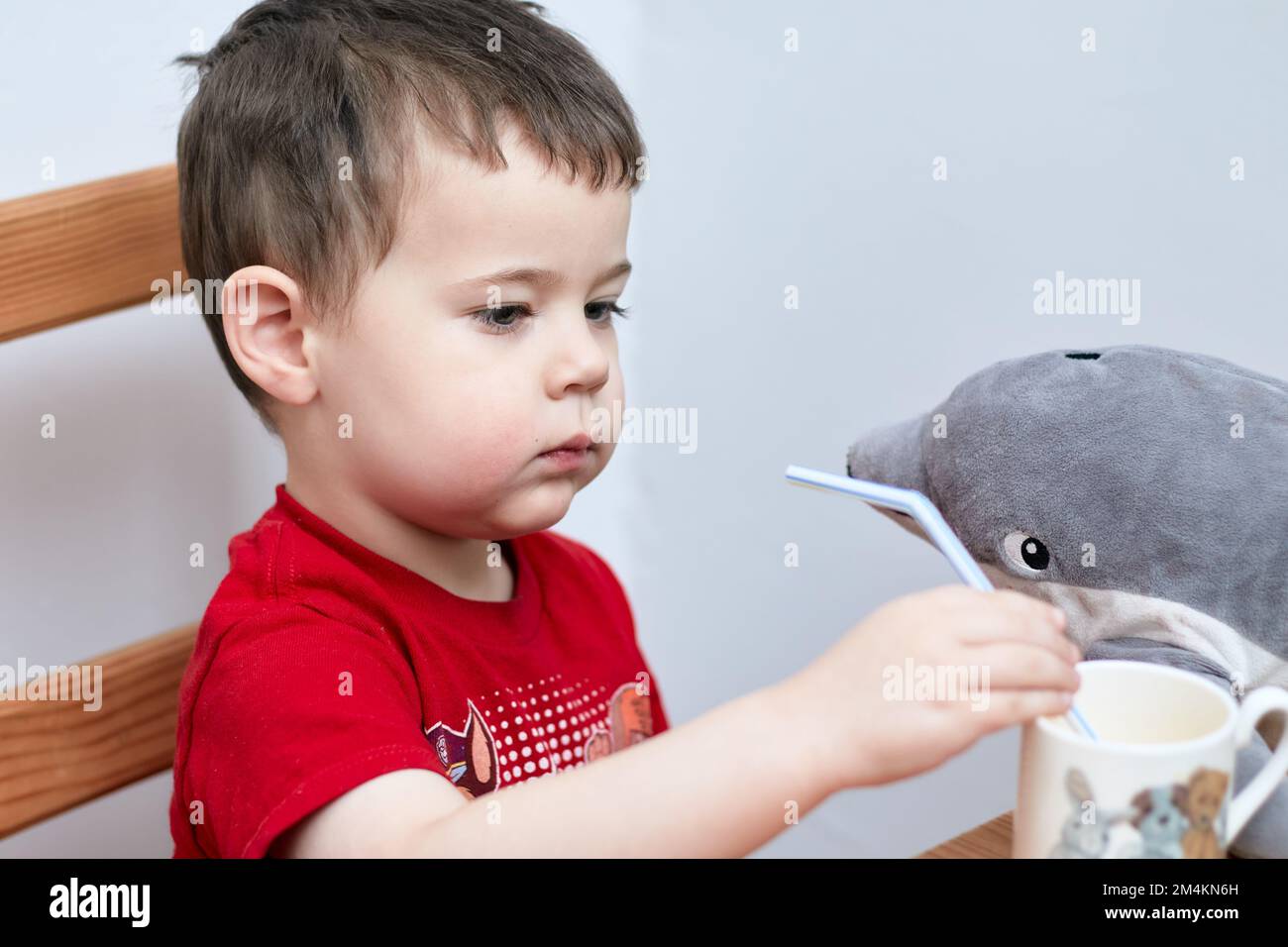 adorable boy drinking orange juice through a plastic straw Stock Photo