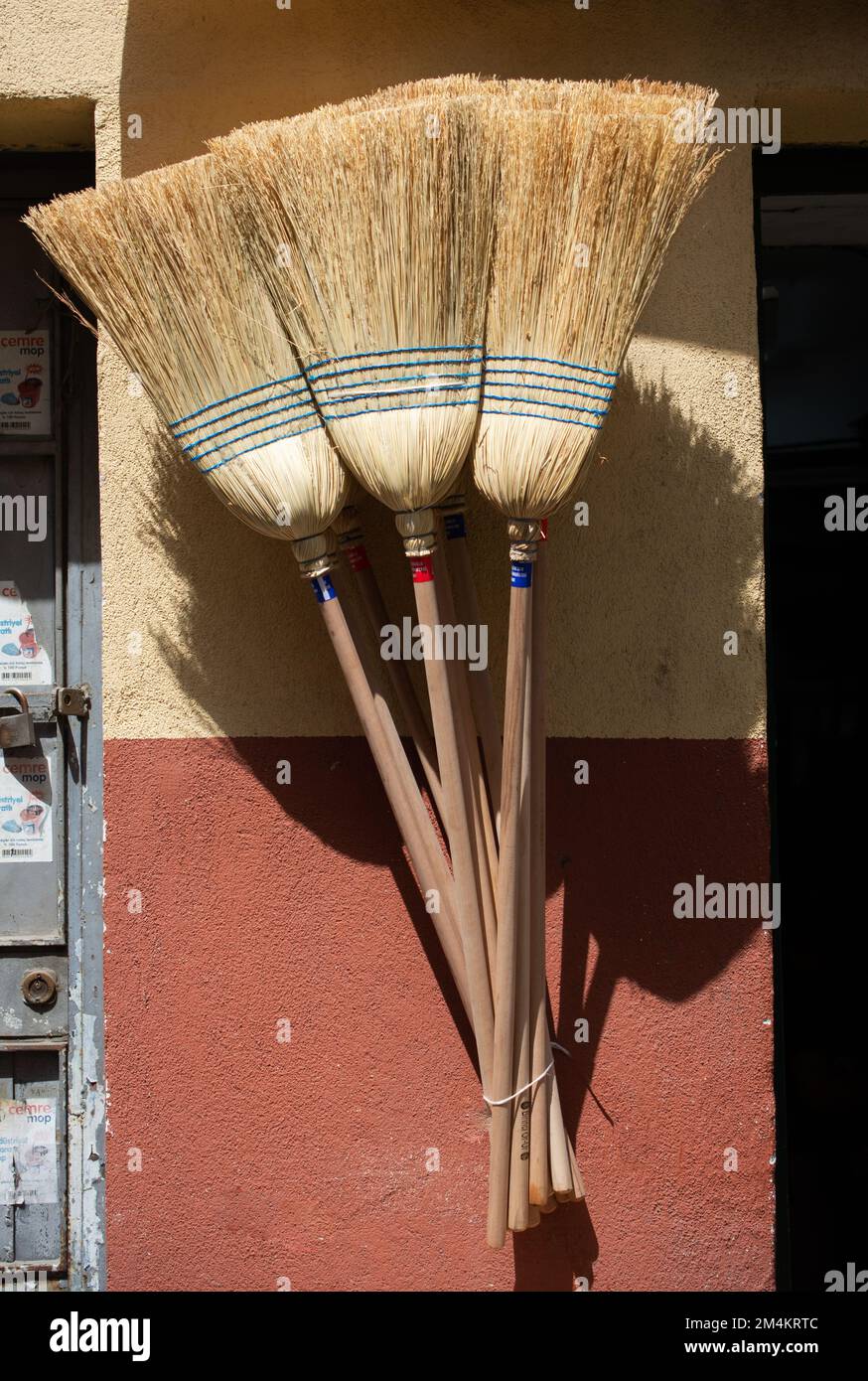 A verticl shot of a set of brooms hanging on the wall under the sunlight Stock Photo