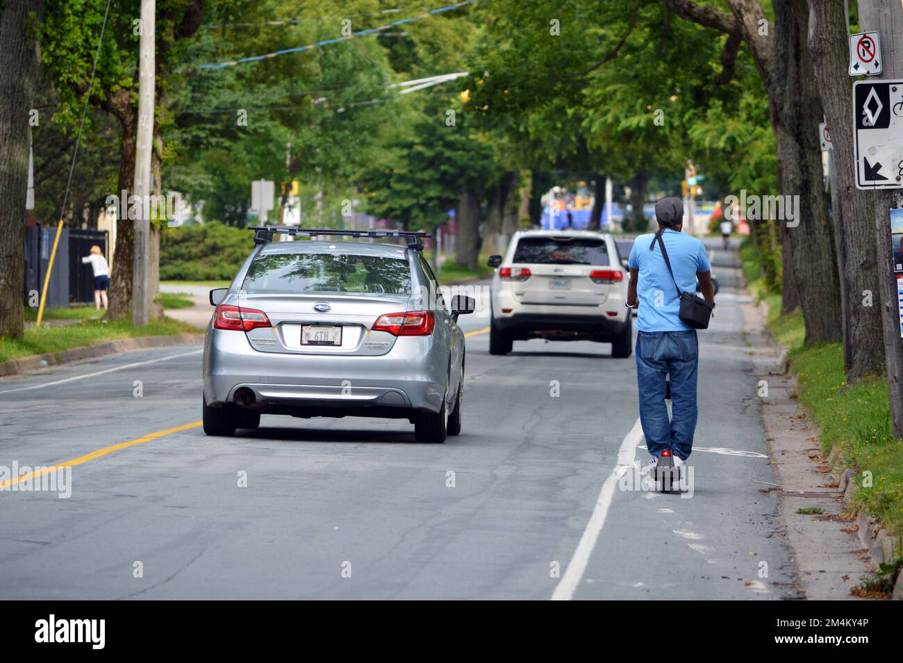 Man riding scooter in the Bell Road painted bike lane, alongside car traffic, in Halifax, Nova