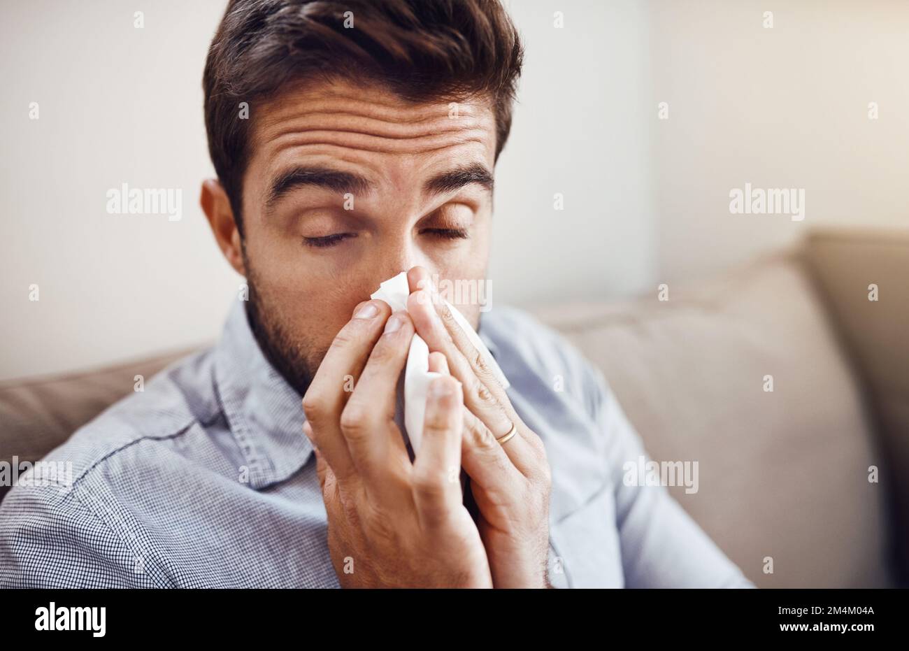 This fever just wont go away. a handsome young man blowing his nose