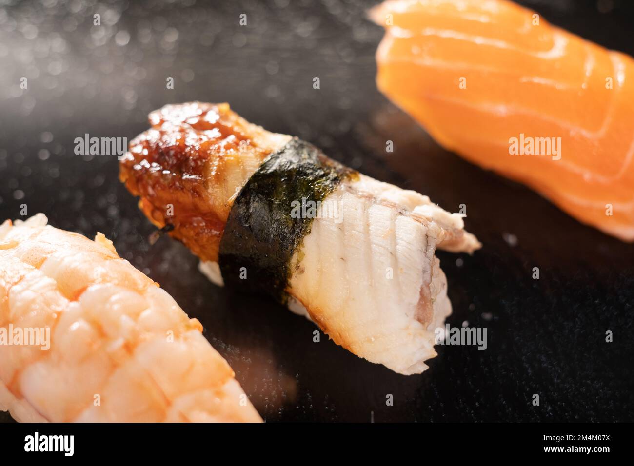 Nigiri sushi with salmon, grouper, eel, tuna and prawn on black stone