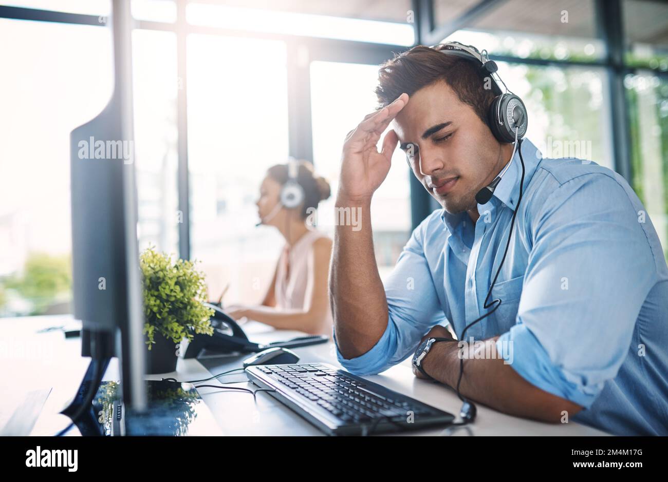 You try your best to help, but sometimes...a handsome young man looking stressed while working in a call center. Stock Photo