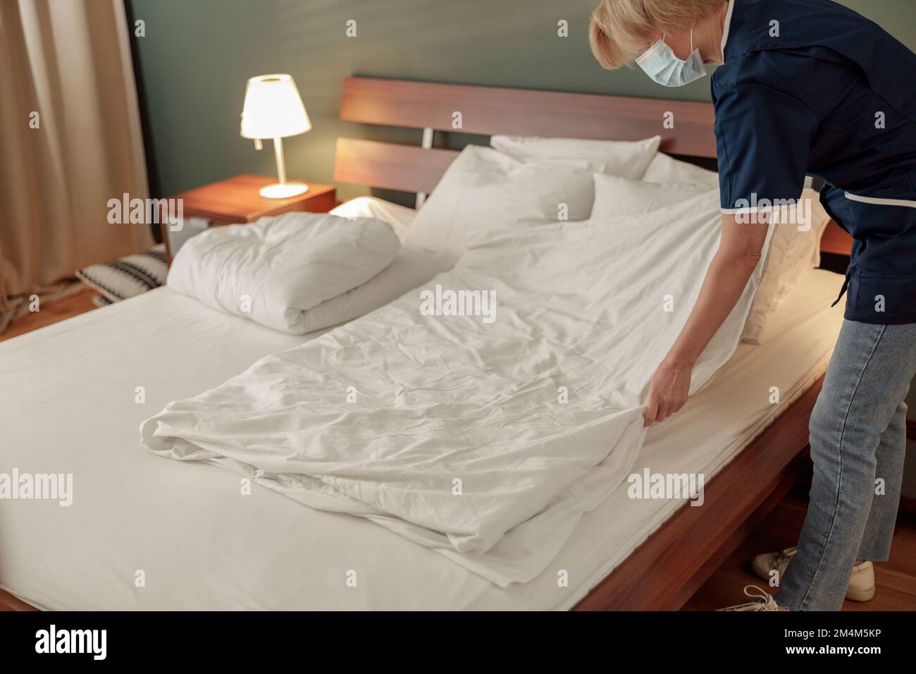 Cleaning lady doing housekeeping and making bed in hotel room. Cleaning service concept Stock