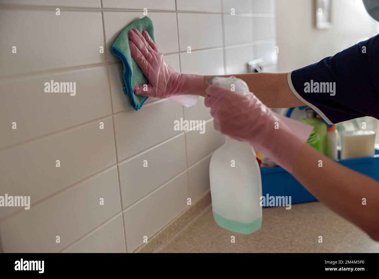 Cleaning lady washing tile wall with detergent and rag. Hygiene, purity