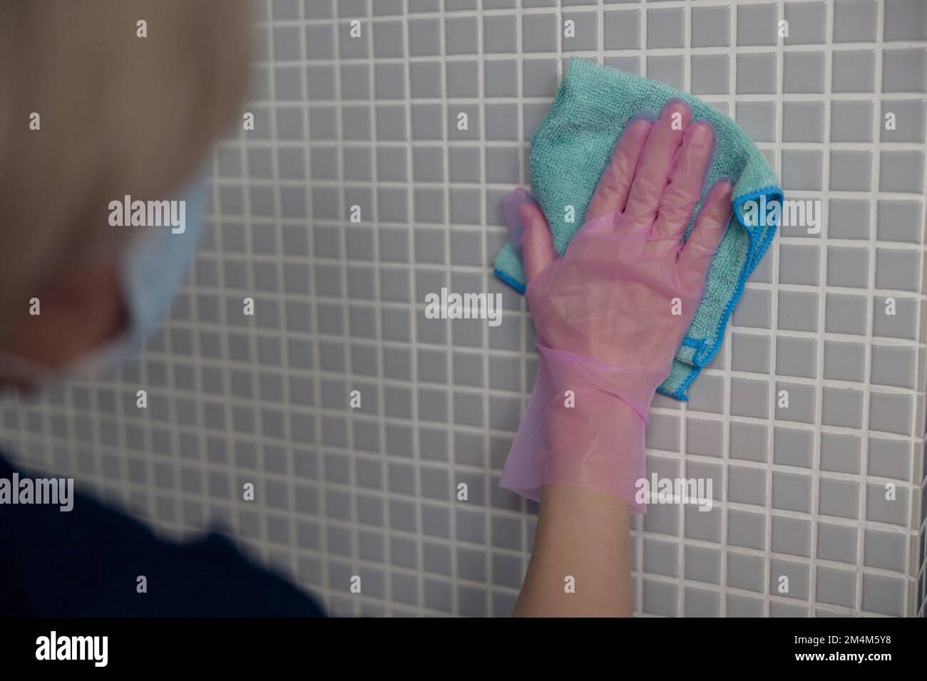 Cleaning lady washing tile wall with detergent and rag. Hygiene, purity