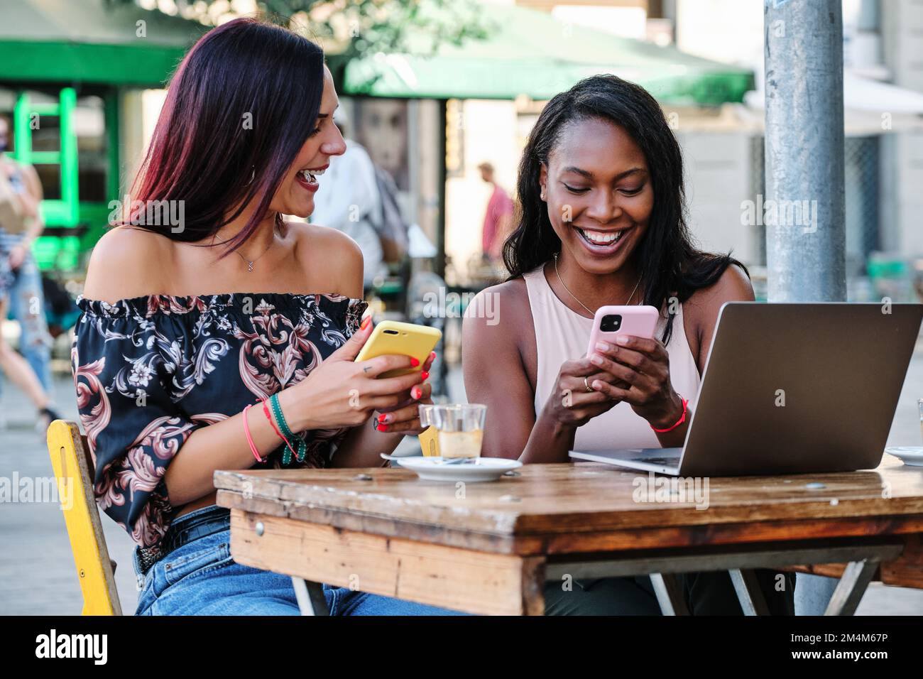 Two woman using mobiles while sitting in a cafeteria Stock Photo