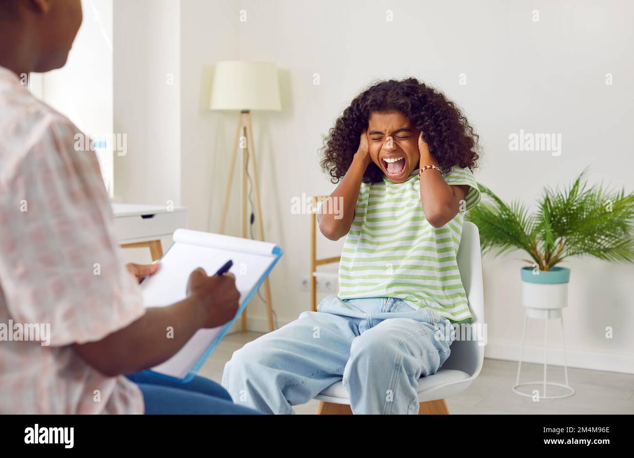 Angry teenage girl screams during session with psychologist, denying communication and treatment. Stock Photo