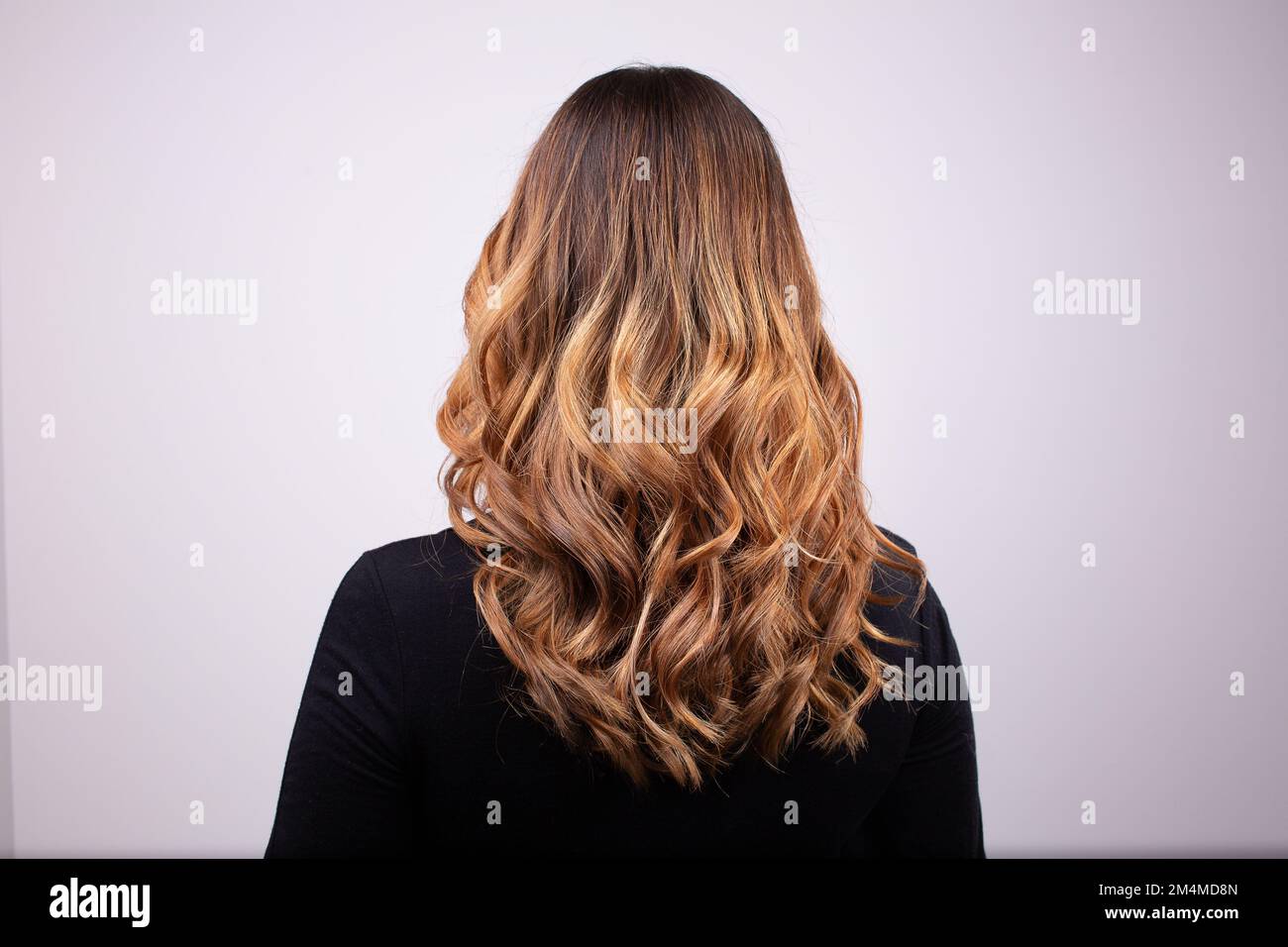 Back view portrait of beautiful curly dark blonde woman wearing black sweater. High quality photo Stock Photo