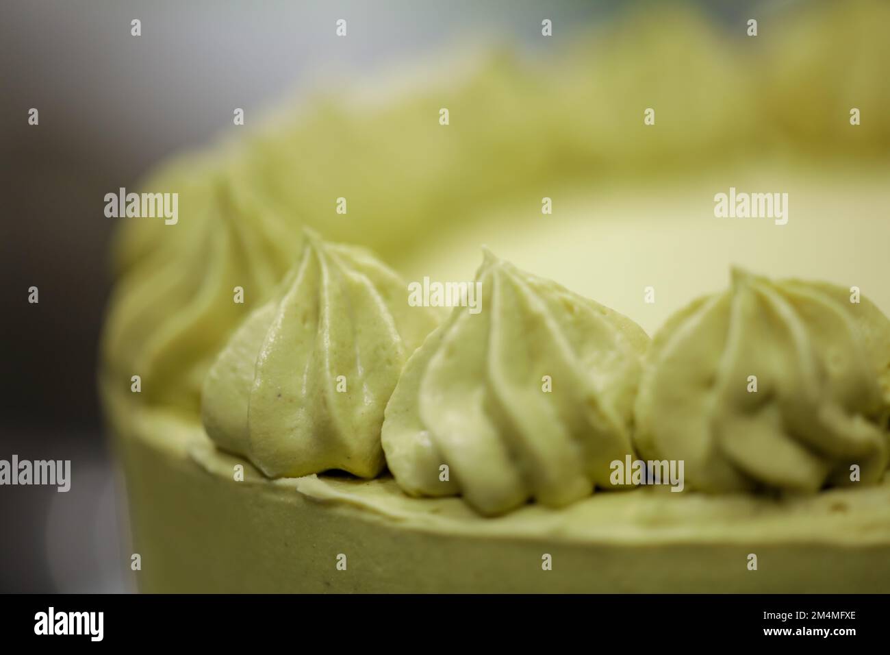 pastry chef designer making swirls with piping bag pistachio cream filling on layered green frosted chocolate cake Stock Photo