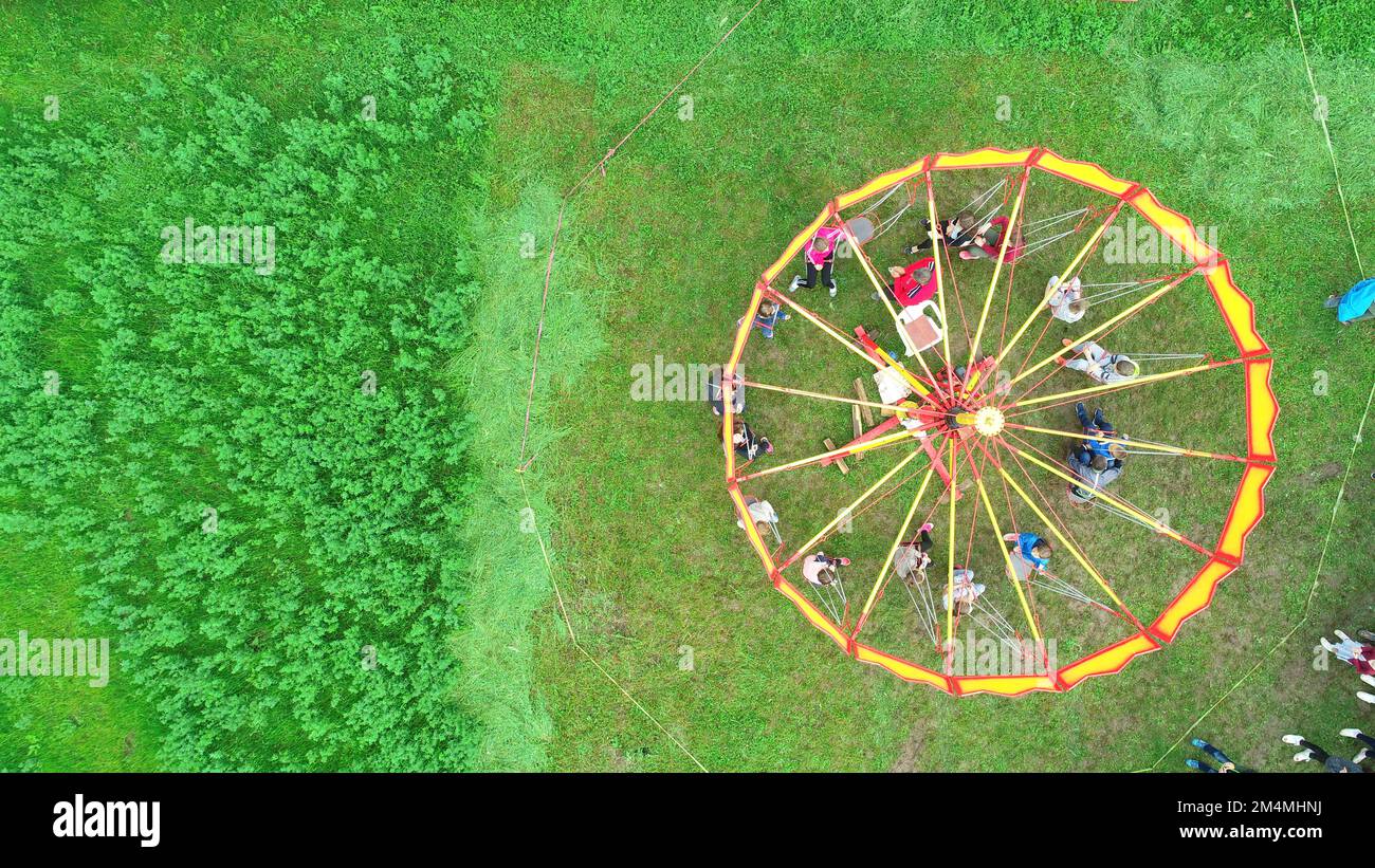 Carnival Merry Go Round aerial top view. Drone tracking rotation shoot.  Stock Photo