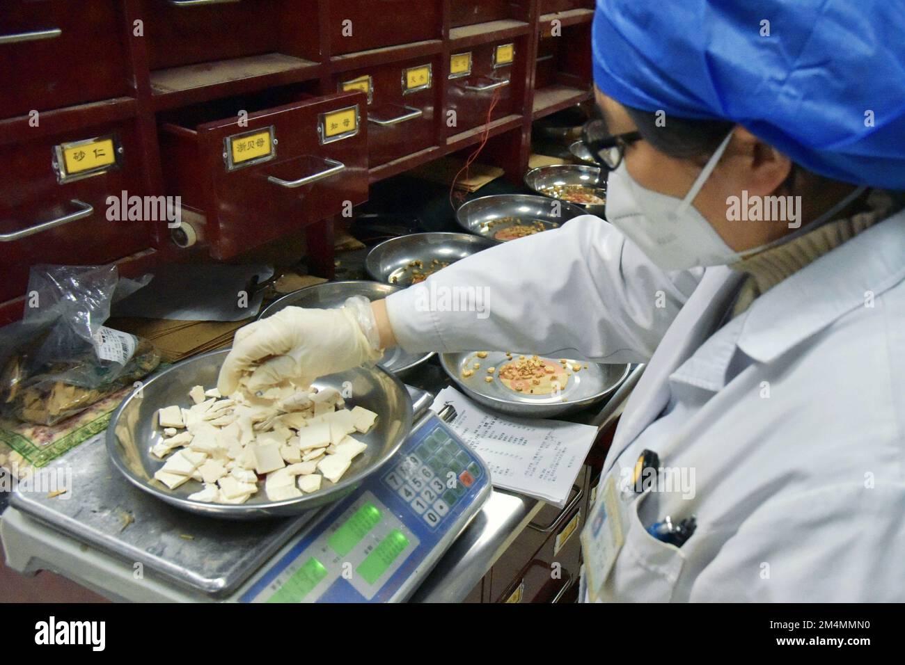 RUGAO, CHINA - DECEMBER 22, 2022 - A traditional Chinese medicine practitioner weighs herbs for mixing traditional Chinese medicine prescriptions at t Stock Photo