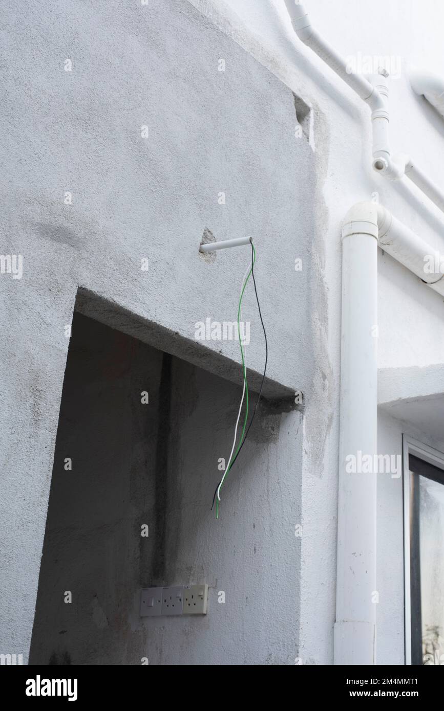 3 electric wires laying out from the concrete wall Stock Photo Alamy