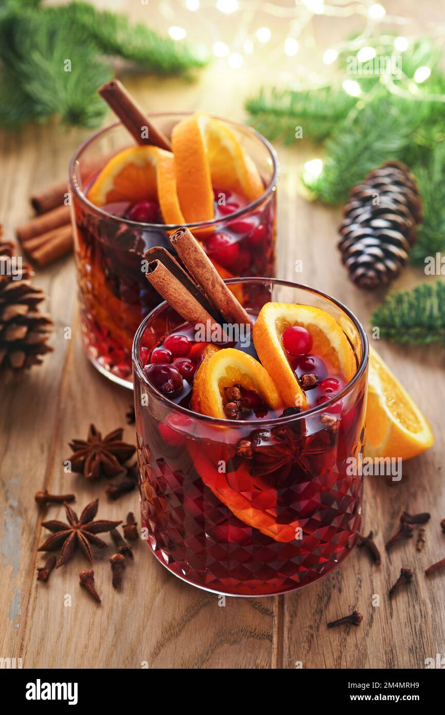Christmas hot mulled wine. Glasses of mulled wine with aromatic spices cinnamon, anise, sugar and fir tree branches with bokeh and decorations. Tradit Stock Photo