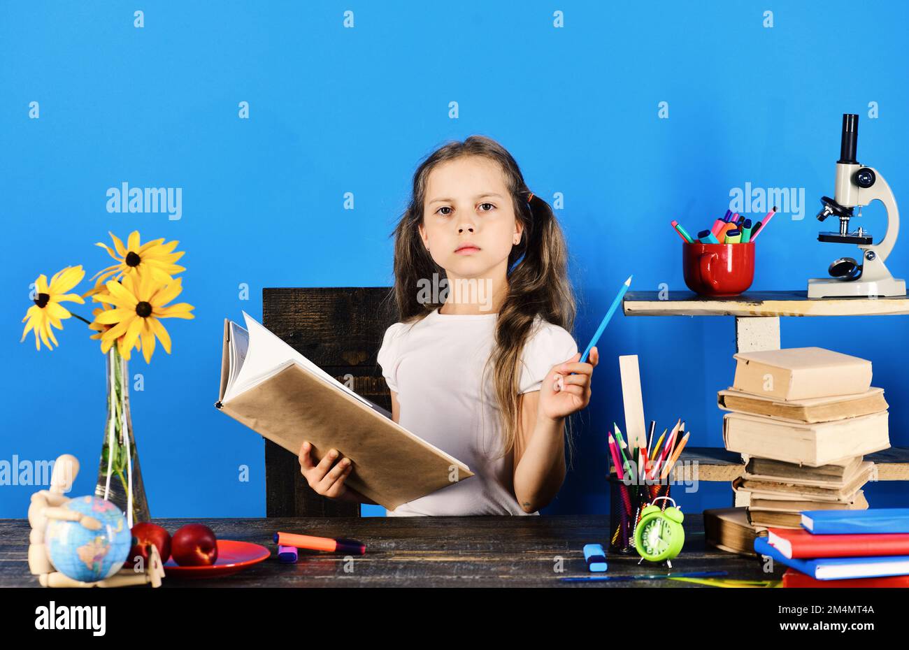 Schoolgirl sits at desk with serious face Stock Photo - Alamy