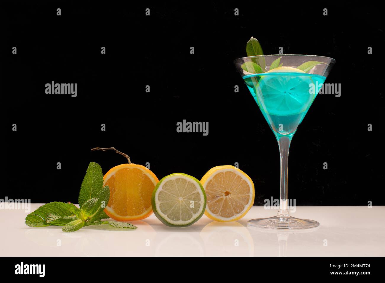 Blue cocktail glass with fruits on black background Stock Photo - Alamy