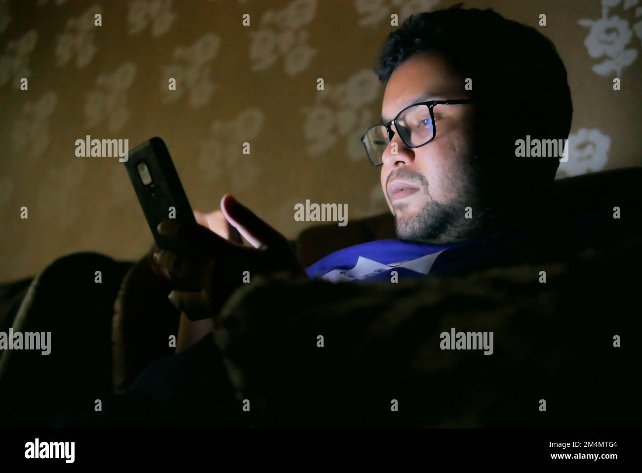 young men sitting on sofa using smart phone at night  Stock Photo
