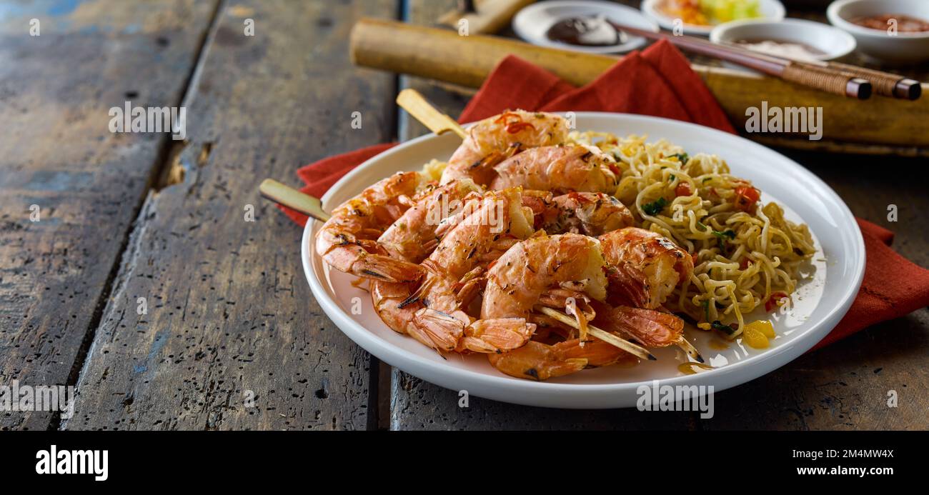 Delicious shrimp scampi dish with noodles served on plate on lumber table during lunch in Asian restaurant Stock Photo