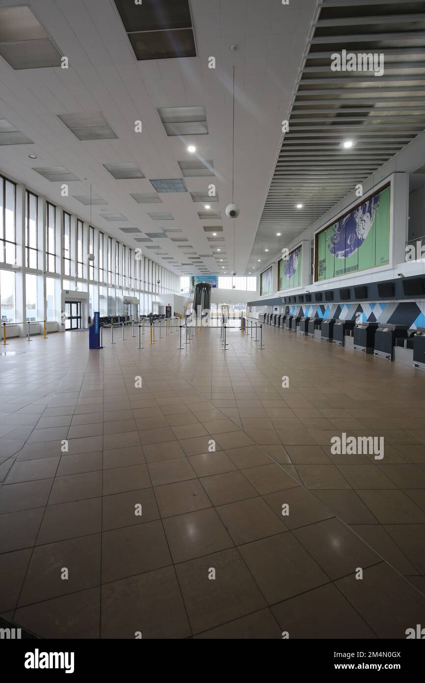 Glasgow Prestwick Airport. Ayrshire Scotland. March 2022.   The deserted terminal building concourse awaiting passengers and trade. Above check in desks is  hoardings promoting COP 26 still on view Stock Photo