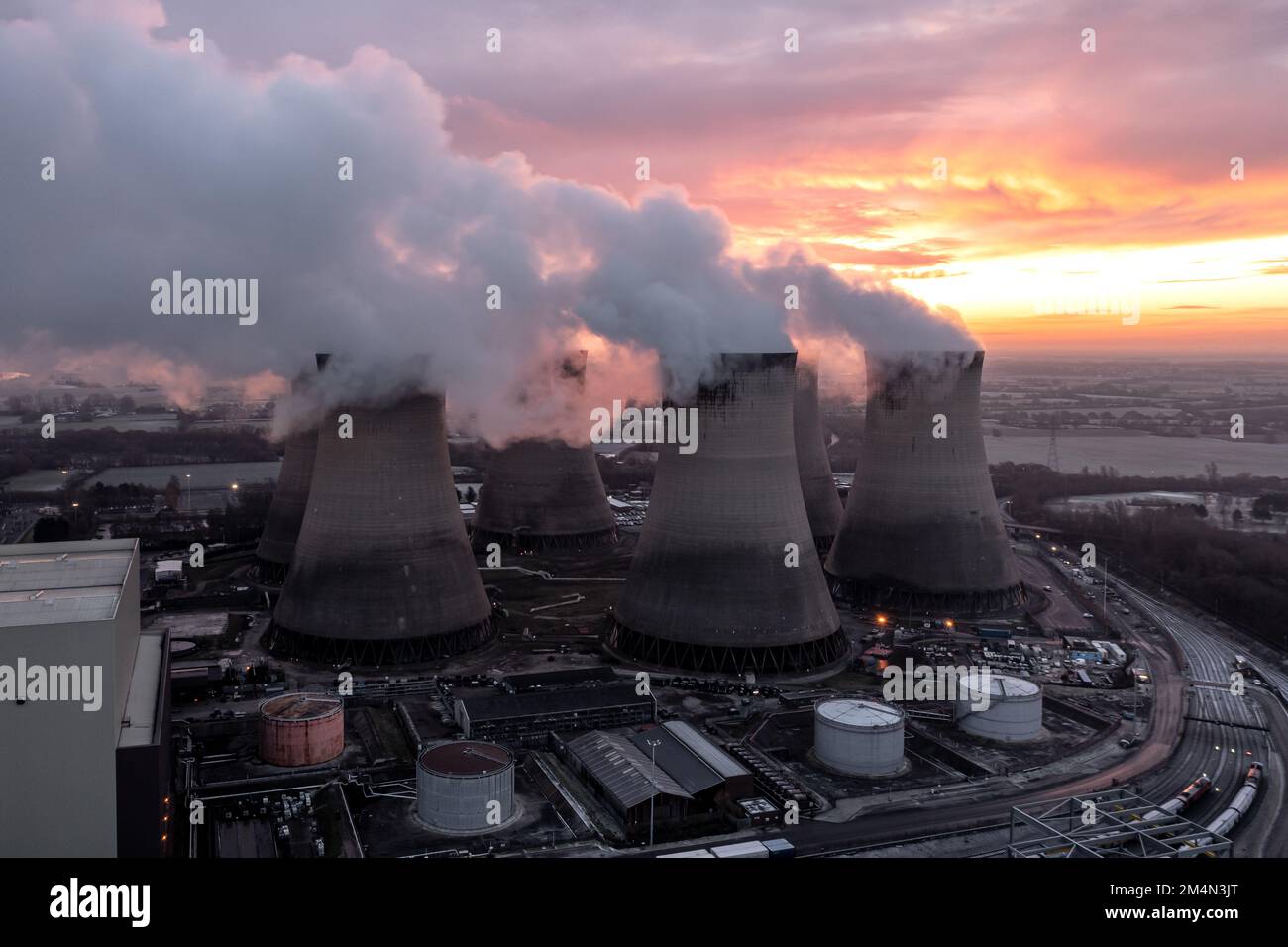Aerial view of dirty coal fired power station cooling towers polluting the atmosphere with carbon dioxide emissions at sunset Stock Photo
