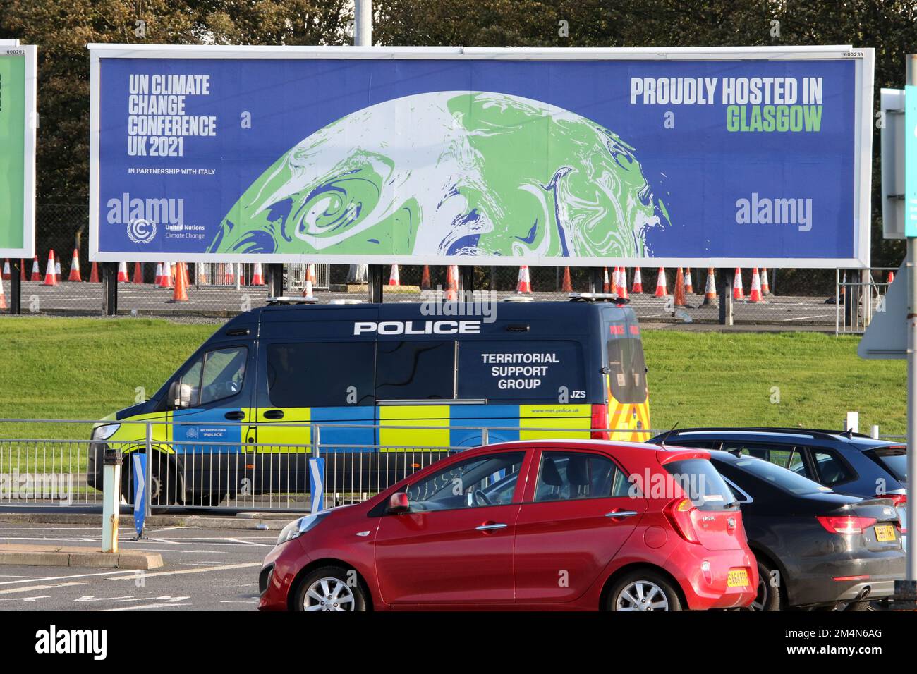 Glasgow Prestwick Airport, Prestwick, Ayrshire, Scotland, UK. Image shows large advertising hoarding promoting the UK Climate Change conference being held in Glasgow 2021. Known as COP 26. A Police van passes in front of he hoarding Stock Photo